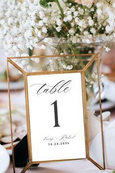 a table number sign sitting on top of a table next to a vase filled with flowers