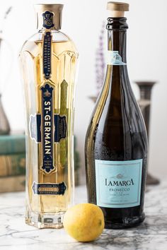 two bottles of liquor sitting on top of a table next to an orange and a lemon