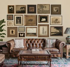 a living room filled with furniture and lots of framed pictures on the wall above it