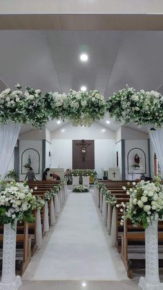 an aisle decorated with white flowers and greenery for a wedding ceremony at the church