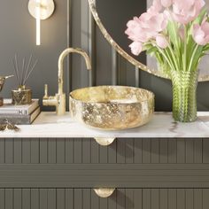 a bathroom counter with a sink, mirror and flowers