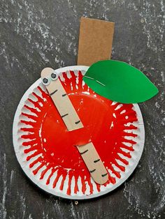 a paper plate with an apple on it and a green leaf cut out of cardboard