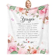 a woman holding up a pink floral blanket with the words yoga on it and roses