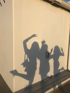 the shadow of two people standing in front of a white wall with an open door