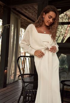 a woman in a white dress standing on a porch