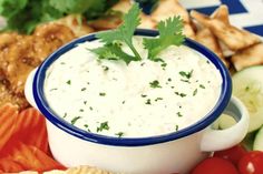 a bowl of dip surrounded by vegetables and crackers