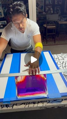 a man is making an art project with acrylic paint