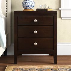 a night stand with three drawers and a blue vase on the end table next to it