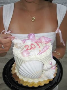 a woman holding a cake decorated with seashells