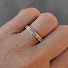 a person's hand with a gold ring on it and two diamonds in the middle