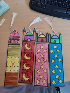 three bookmarks with different designs on them sitting on a desk next to a keyboard