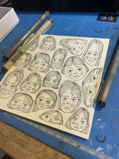 a bunch of faces drawn on top of a piece of paper next to some markers