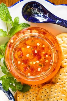 a plate with crackers and a jar of salsa on it next to a spoon