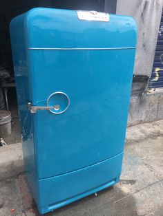 an old blue refrigerator sitting on the sidewalk