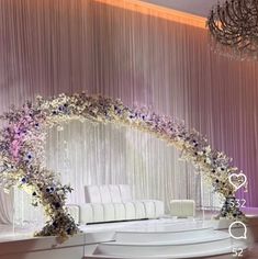 a white couch sitting under a chandelier next to a table with flowers on it