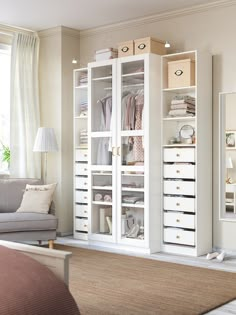 a living room filled with furniture and lots of white storage space next to a window