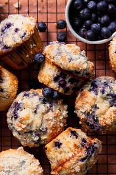 blueberry muffins on a cooling rack next to a bowl of blueberries