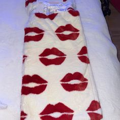 a white bed with red lips on it and a blanket that is made to look like a sleeping bag