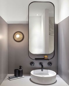 a white sink sitting under a bathroom mirror next to a wall mounted faucet