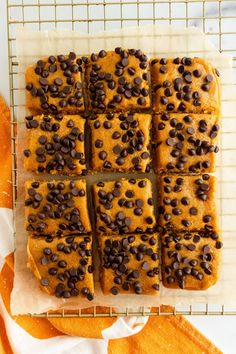 chocolate chip cookie bars on a cooling rack with an orange towel next to the tray