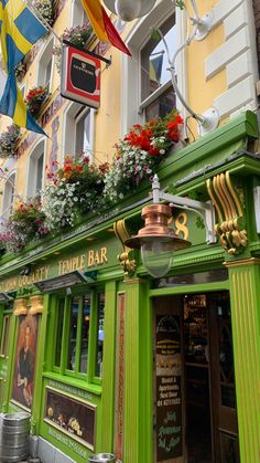 a green building with flowers on the windows and decorations hanging from it's sides