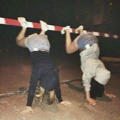 two young boys are playing with a red and white striped barricade at night