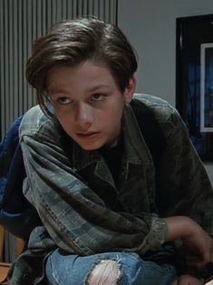 a young boy sitting on top of a wooden table