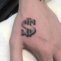 a hand with a dollar sign tattoo on it