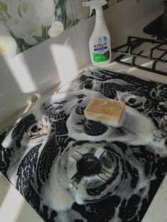 a stove top with soap on it and a bottle of cleaner next to it in a kitchen