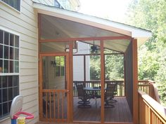 an enclosed patio with table and chairs on the back deck, surrounded by wooded area