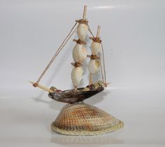 a small ship made out of shells on a white surface with no people around it