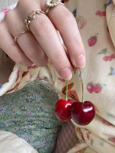 a close up of a person holding two cherries