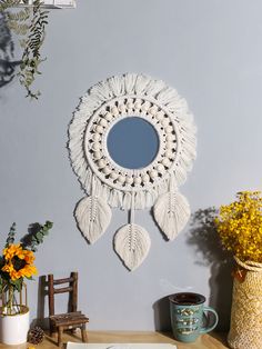 a mirror hanging on the wall above a table with flowers and plants in vases