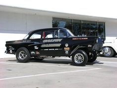 a black and white truck parked in front of a building next to a white car