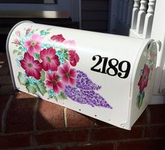 a white mailbox with flowers painted on it's side and the number 209