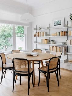 a dining room table with chairs and bookshelves