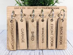 four wooden keychains with engraved names on them are shown in front of a potted plant