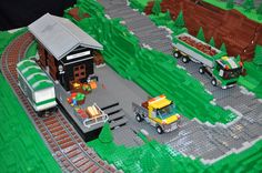 there is a lego model of a train station with cars and trucks on the tracks