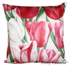 a red and white pillow with pink flowers on the front, sitting on a white background