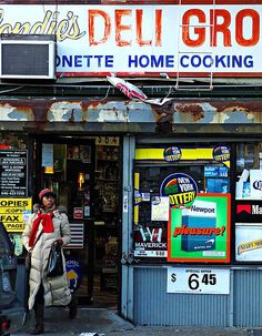 a woman walking past a deli grocer store