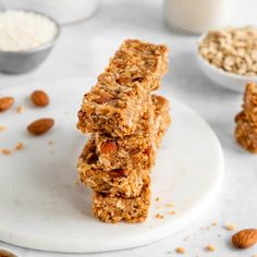 three granola bars stacked on top of each other with nuts and milk in the background