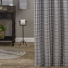 a bathroom with a shower curtain, rug and toilet paper dispenser on the floor