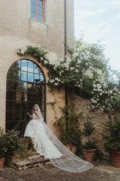 a woman in a wedding dress is standing on the steps with her veil blowing in the wind