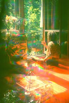 a woman sitting on a couch in front of a window with sunlight streaming through it