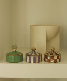 three decorative containers are sitting on a shelf