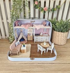 a doll house with furniture and accessories on a wooden table in front of a fence