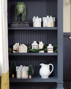 a book shelf filled with white houses and greenery on top of it's shelves