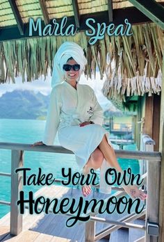 a woman sitting on top of a wooden deck next to the ocean with text overlay that reads, take your own honeymoon