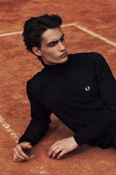 a man sitting on top of a tennis court holding a racquet