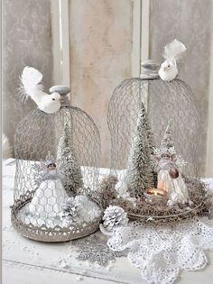 two white birds sitting on top of wire cages with pine trees and snowflakes